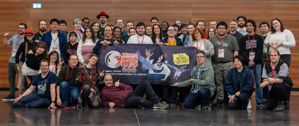 Photo de groupe de l'équipe organisatrice de Jonetsu 666 entourant la bannière promotionnelle de la convention. YOSHINARI Yoh et TSUTSUMI Naoko sont au milieu de l'équipe.